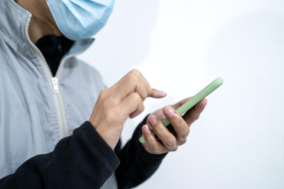 Cold patient wearing protective mask while using mobile phone