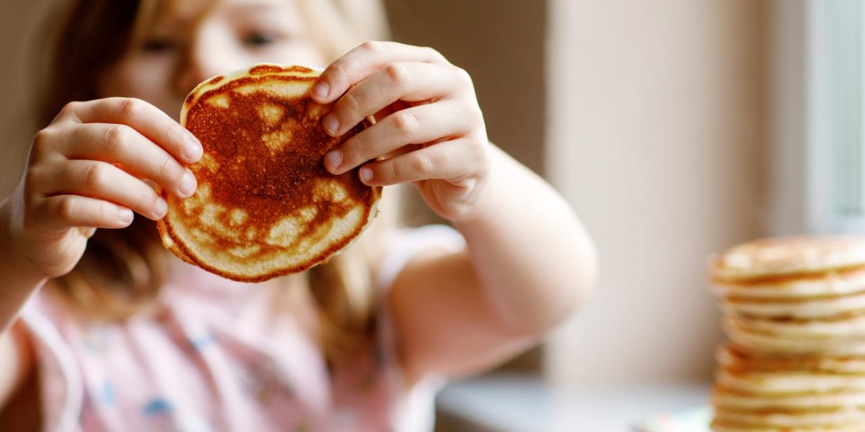 preschool girl holding pancake -foods to feed your sick toddler