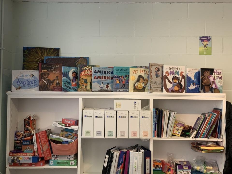 A shelf of books, games and folders are stacked up behind Decode Project co-founder and executive director LaToya Whitlock's desk.