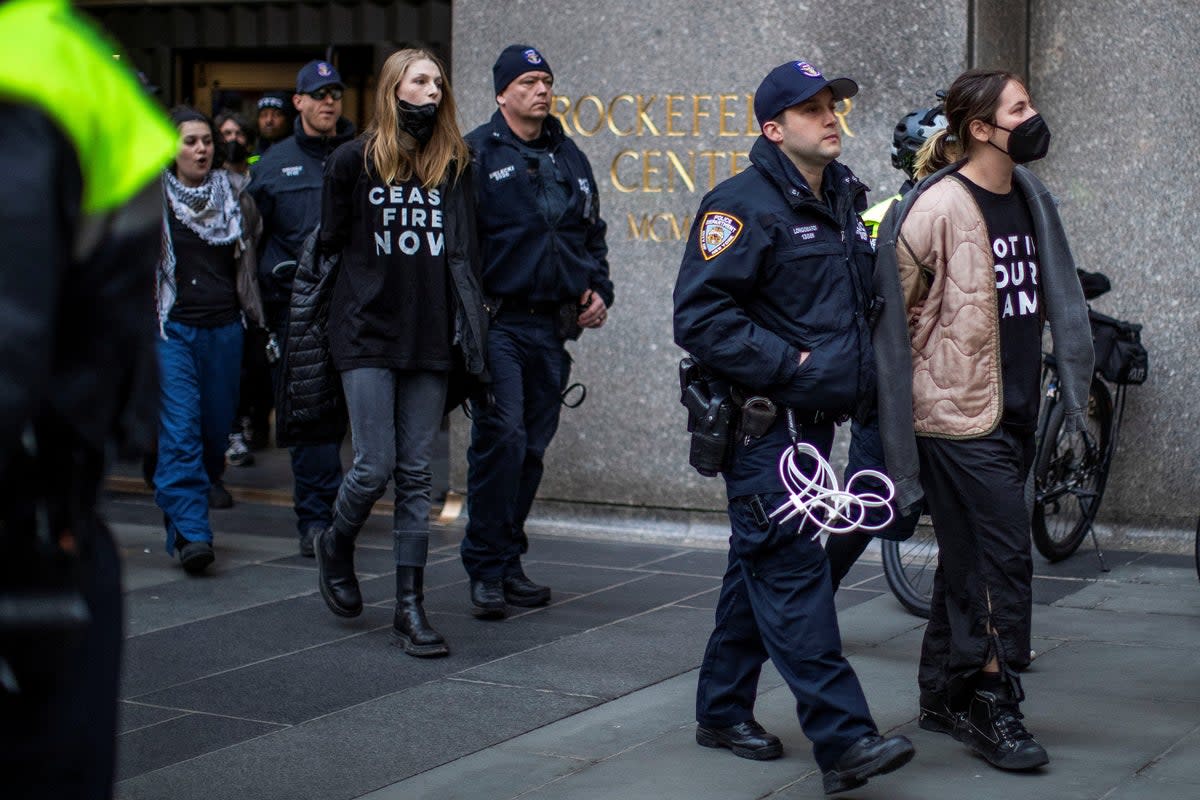 Schafer and protesters being lead out of the Rockefeller Centre (REUTERS)