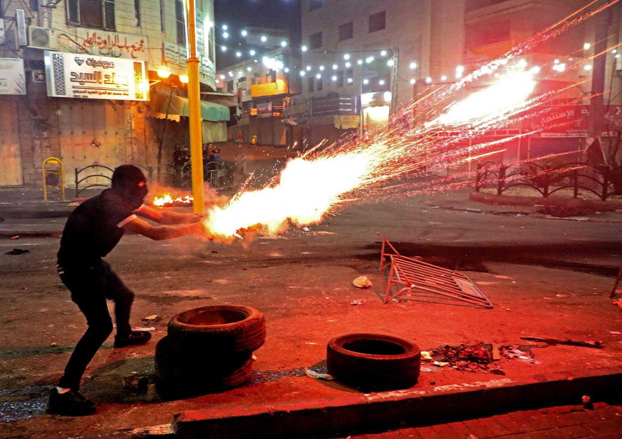 Un manifestante palestino lanza bengalas en medio de enfrentamientos con soldados israelíes en el centro de la ciudad de Hebrón en Cisjordania (AFP via Getty Images)