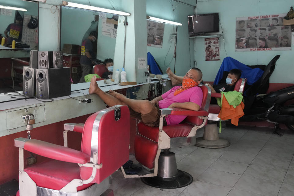 FILE - In this Sept. 16, 2021, file photo, barbers wait for customers after reopening their shop following easing of COVID restrictions in Quezon city, Philippines. The World Bank on Tuesday, Sept. 28, 2021, cut its economic growth forecast for developing countries in East Asia due to the impact of the coronavirus’s delta variant and called on governments to help the poor and small businesses avoid long-term damage. (AP Photo/Aaron Favila, File)