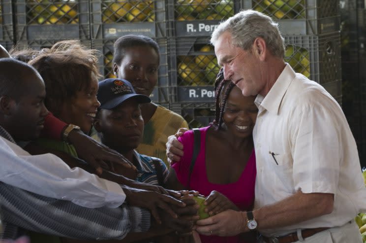 Former President George W. Bush, right, shares a moment with workers of a mango warehouse in Port-au-Prince, Haiti, Tuesday Aug. 10, 2010. Bush arrived in Haiti on Tuesday, to visit organizations, supported by the Clinton-Bush Haiti Fund, and to reassure investors that the money spent would help the nation 