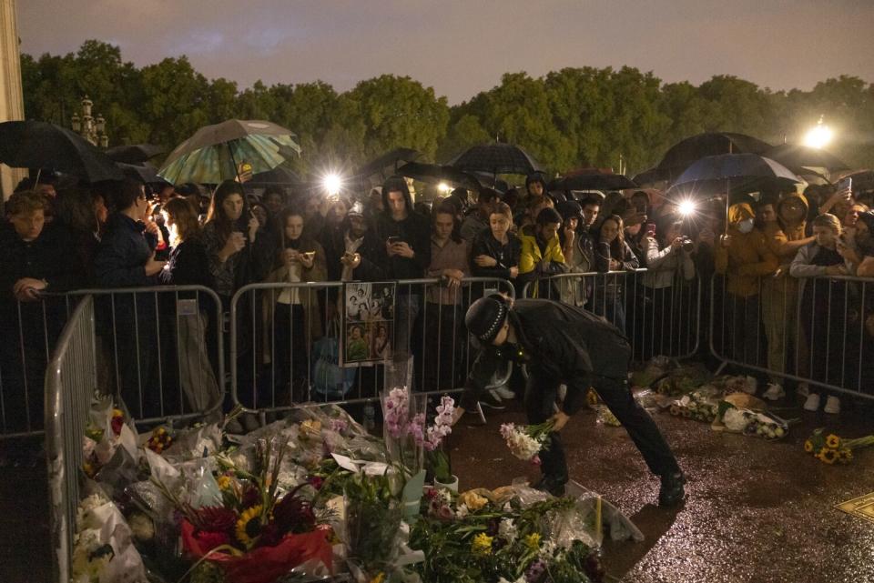 A female police officer places a bouquet of flowers outside Buckingham Palace.