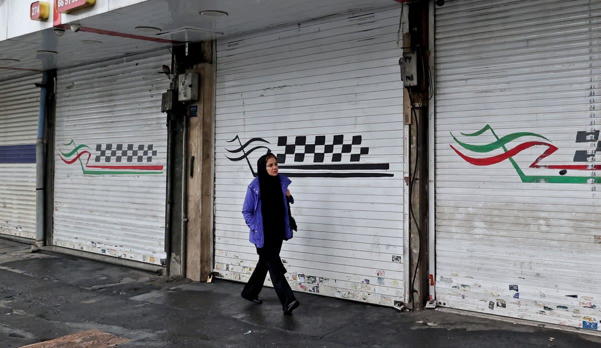 A woman walks past a closed shop along Satarkhan street in Iran's capital Tehran (AFP via Getty Images)