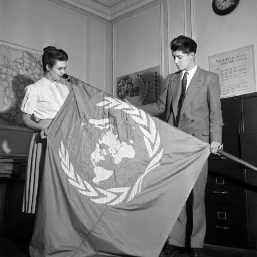 A picture released on August 20, 1948, shows employees of the Paris UN Information Office unfolding the UN flag which was to be hoisted in France for the third General Assembly of the United Nations which adopted the Universal Declaration of Human Rights