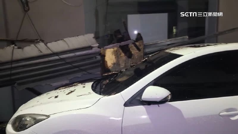 白色轎車受損較嚴重，木質招牌插在擋風玻璃上。