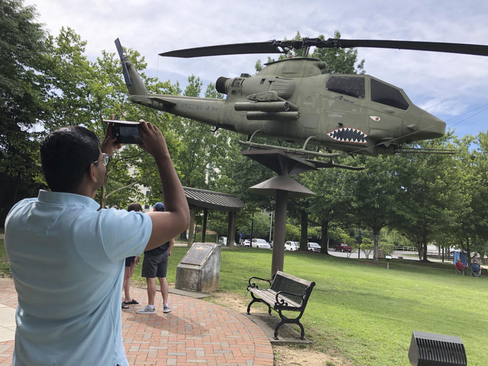 In this June 26, 2019 photo, Ashish Bibireddy, 23, takes a photo of a U.S. military attack helicopter at Cumberland Square Park in Bristol, Va. Ten medical students were on a tour of the city organized by a medical school with the aim of luring them to practice in rural communities facing health care shortages after graduation. (AP Photo/Sudhin Thanawala)