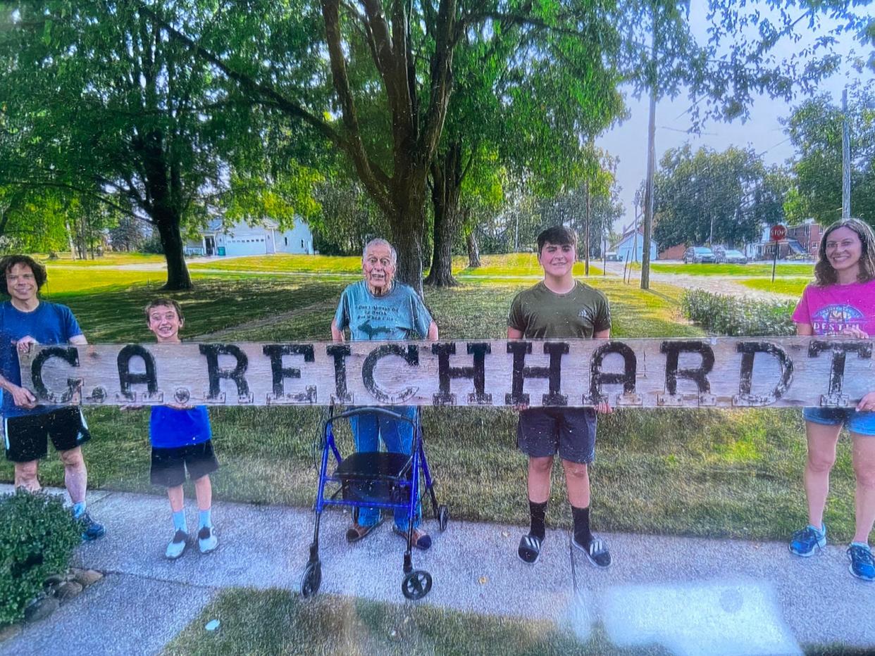 Members of the Reichhardt family hold the sign from their farm.