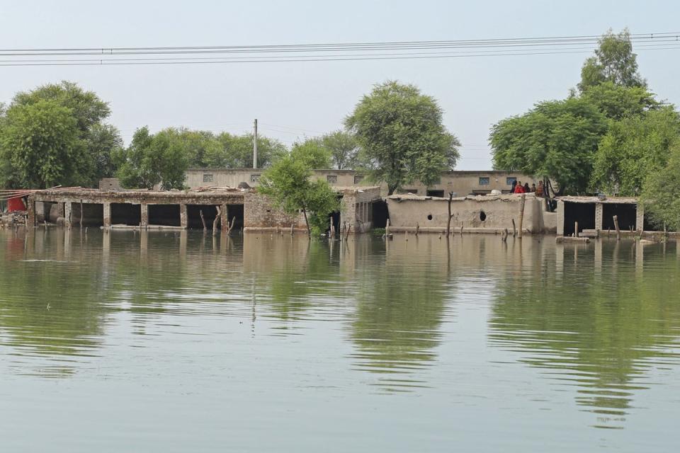 Women sit atop their mud house in Dera Ghazi Khan hit area following heavy monsoon rains (AFP via Getty Images)