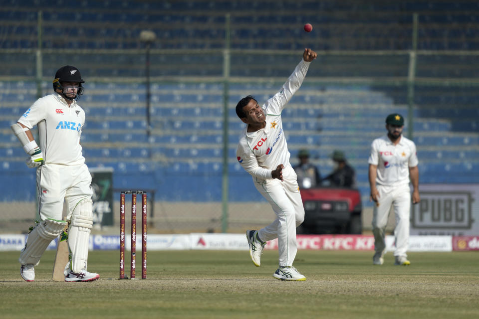 Pakistan's Nauman Ali, center, bowls as New Zealand's Tom Latham, left, watches during the third day of first test cricket match between Pakistan and New Zealand, in Karachi, Pakistan, Wednesday, Dec. 28, 2022. (AP Photo/Fareed Khan)