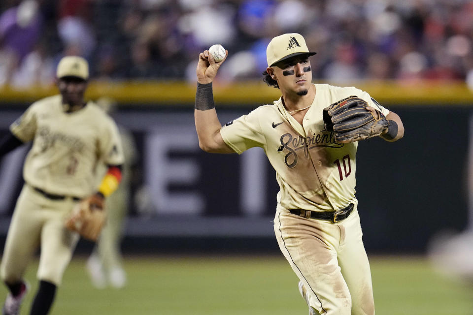 Arizona Diamondbacks third baseman Josh Rojas, right, throws to first base to get out Cleveland Guardians' Steven Kwan as Diamondbacks shortstop Geraldo Perdomo, left, looks on during the fourth inning of a baseball game Friday, June 16, 2023, in Phoenix. (AP Photo/Ross D. Franklin)