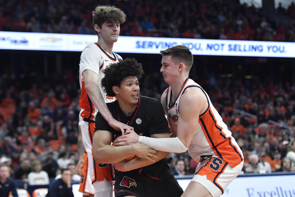 Louisville guard/forward Zan Payne, center, is defended by Syracuse center Peter Carey, left, and guard Justin Taylor during the first half of an NCAA college basketball game in Syracuse, N.Y., Wednesday, Feb. 7, 2024. (AP Photo/Adrian Kraus)