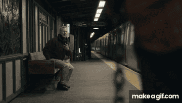 A older white man stands up near a man holding a chain on a subway platform in "Poundcake"