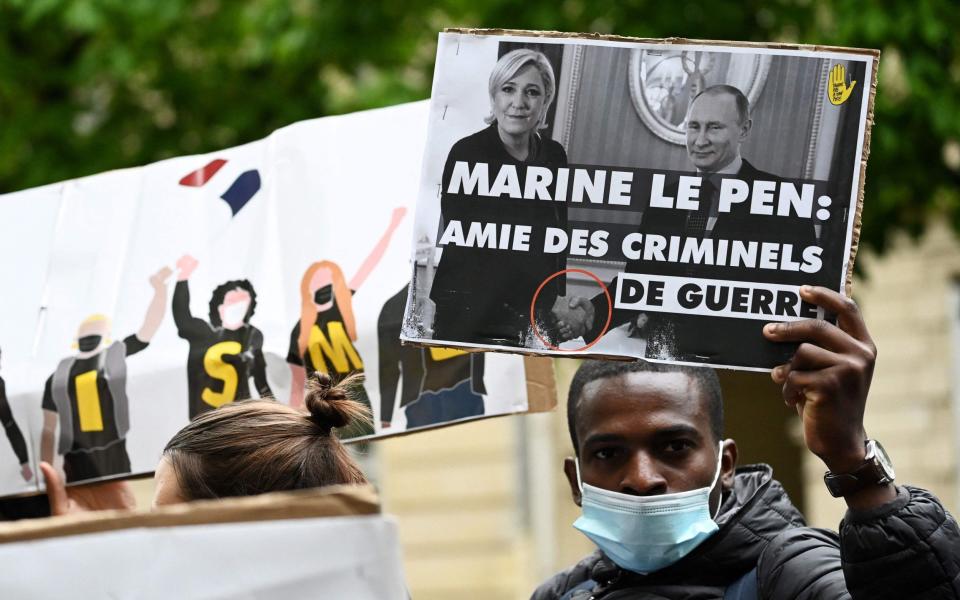 A protester holds a placard of Marine Le Pen and Vladimir Putin, the Russian President during a press conference in Paris on Wednesday - EMMANUEL DUNAND 