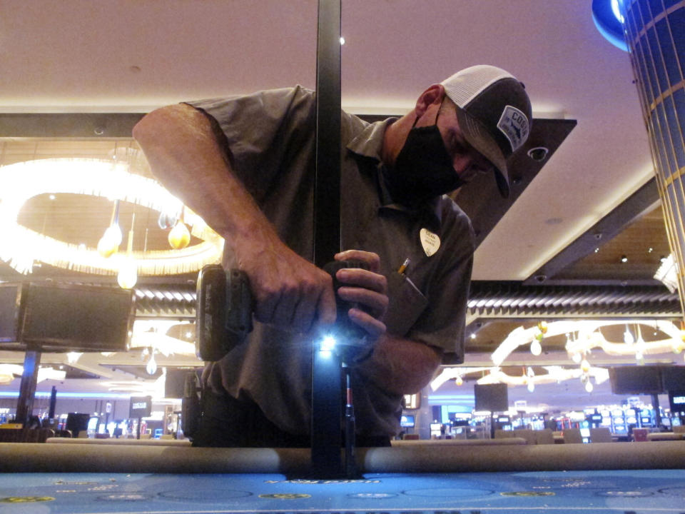 Dean Loveland, a worker at the Hard Rock casino on June 24, 2020, in Atlantic City, N.J., installs plexiglass barriers between player positions at a card table at the casino a week before it was to reopen amid the coronavirus outbreak. On March 11, 2024, an independent report examining New Jersey's response to the pandemic said the state and nation were unprepared for it, adding the state is still underprepared for the next crisis. (AP Photo/Wayne Parry)
