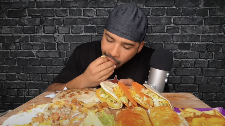 Man eating from a selection of Taco Bell food