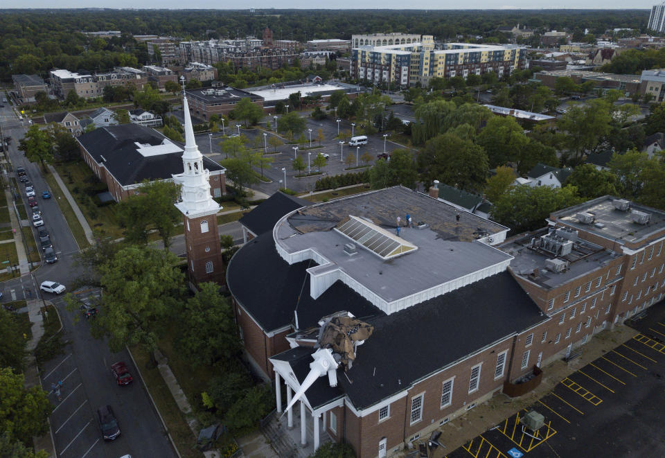 The steeple at College Church in Wheaton, Ill. was toppled during a storm Monday, Aug. 10, 2020, in the northwest suburbs of Chicago, Ill. Church officials check out the damage from the rooftop which also left several trees in the nearby park heavily damaged. (Mark Welsh /Daily Herald via AP)