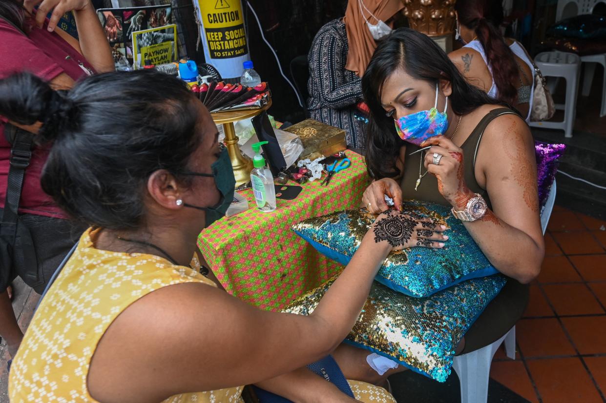 A customer gets hena tattoed on her hands on the eve of the Hindu festival of Diwali in the Little India district in Singapore on November 3, 2021. / AFP / Roslan RAHMAN