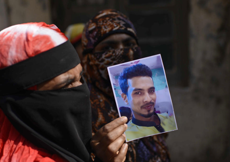 A woman displays a photograph of a relative who died in a fire, outside a morgue in Dhaka, Bangladesh, Thursday, Feb. 21, 2019. A devastating fire raced through at least five buildings in an old part of Bangladesh's capital and killed scores of people. (AP Photo/Mahmud Hossain Opu )