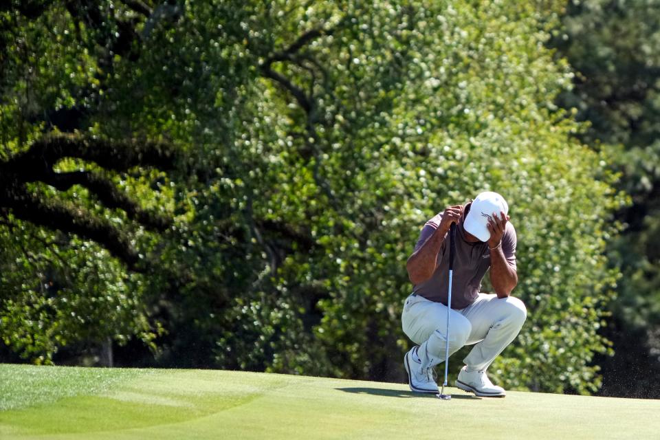 Tiger Woods shields himself from sand blowing out of the bunkers on the 18th hole during Friday's round at the Masters.