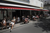 People sit on the terrace of a cafe in Paris, Tuesday, June 2, 2020. Parisians who have been cooped up for months with take-out food and coffee will be able to savor their steaks tartare in the fresh air and cobbled streets of the City of Light once more, albeit in smaller numbers. (AP Photo/Christophe Ena)