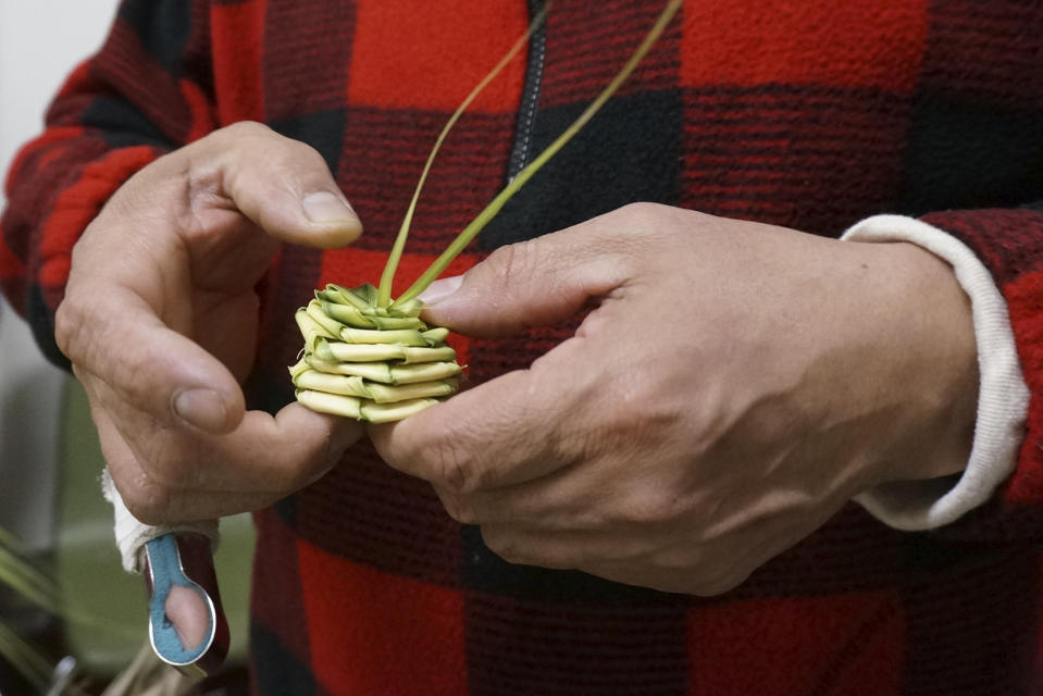 Victor Ramirez weaves a palm frond into a rosette at the Church of the Incarnation in Minneapolis on Wednesday, March 29, 2023. The long-time parishioner at this Catholic church came with his wife and son to help weave elaborate palm frond designs “as a symbol of joy,” he said, which will be blessed at Palm Sunday services. (AP Photo/Giovanna Dell’Orto)