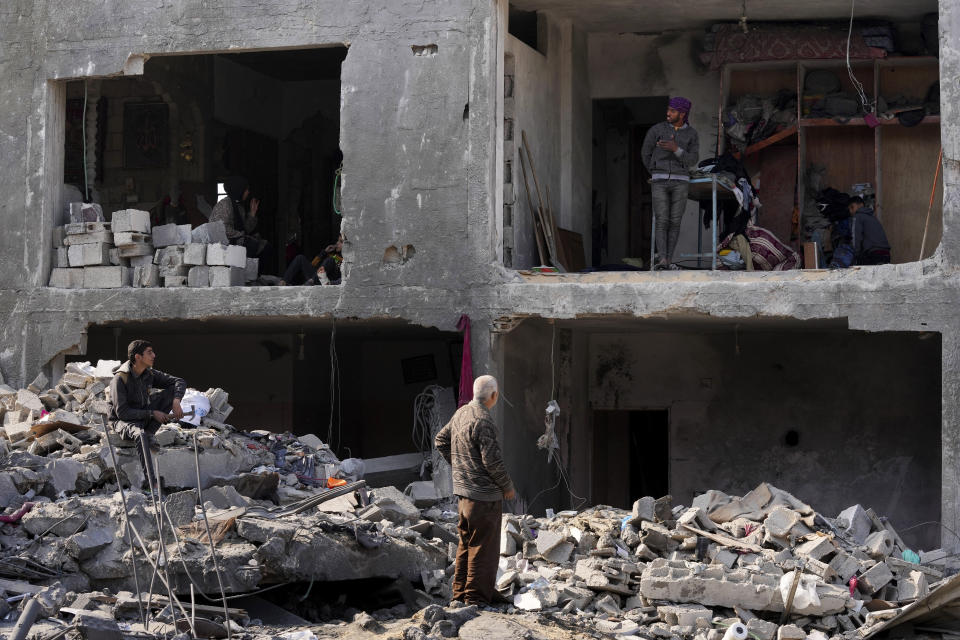 Palestinians look at the destruction of the Al-Gatshan family building after an Israeli strike in Nusseirat refugee camp, central Gaza Strip, Monday, Dec. 18, 2023. (AP Photo/Adel Hana)