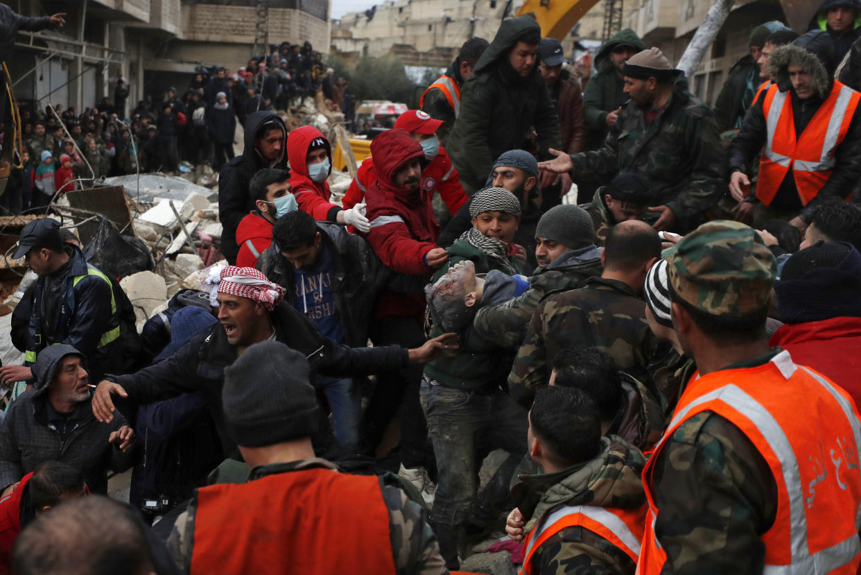 Civil defense workers and security forces carry an earthquake victim as they search through the wreckage of collapsed buildings in Hama, Syria.