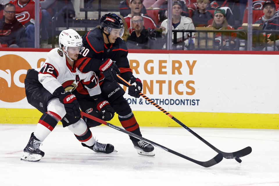 Carolina Hurricanes' Sebastian Aho (20) and Ottawa Senators' Thomas Chabot (72) reach for the puck during the second period of an NHL hockey game in Raleigh, N.C., Wednesday, Oct. 11, 2023. (AP Photo/Karl B DeBlaker)