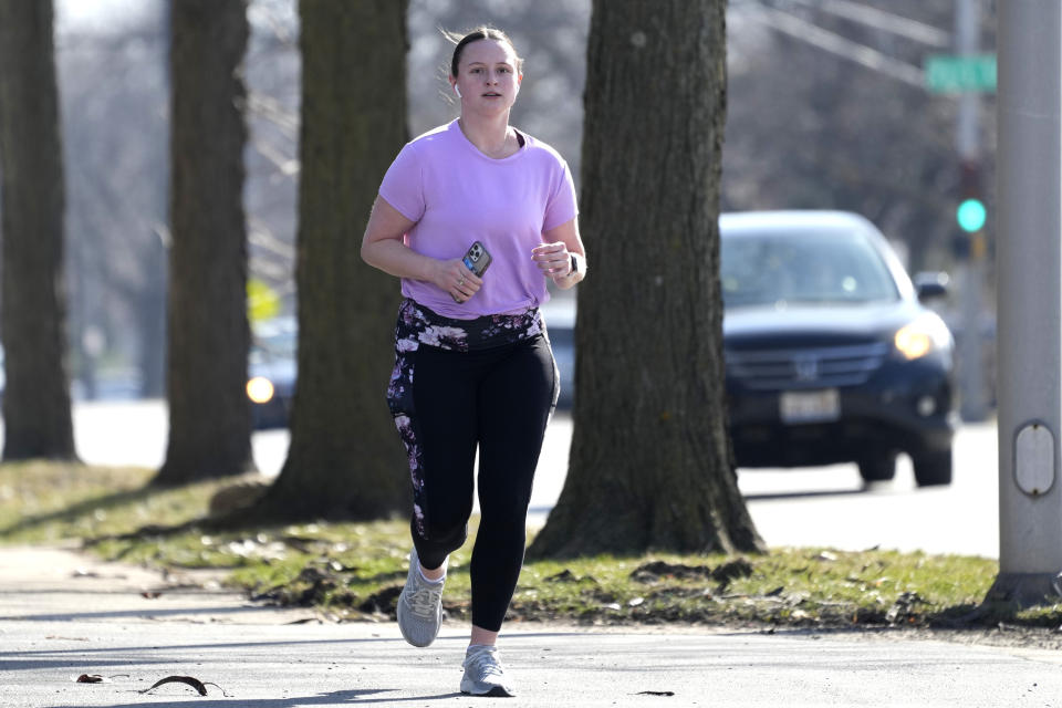 A runner runs on the side walk in Arlington Heights, Ill., Monday, Feb. 26, 2024. Record warmth is expected today and Tuesday. All time February highest temperature records could also be tied or broken in Illinois. (AP Photo/Nam Y. Huh)