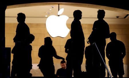 Customers stand beneath an Apple logo at the Apple store in Grand Central station in New York City, July 21, 2015. REUTERS/Mike Segar