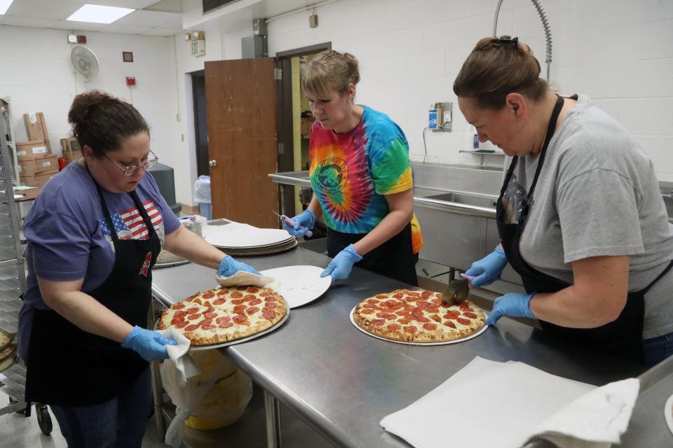 (From left) Machell McCain, Kim Thompson and Lyn Duemmel, who all work in food services for the South-Western City School District, prepare pizzas for students during a lunch period Jan. 19 at Grove City High School.