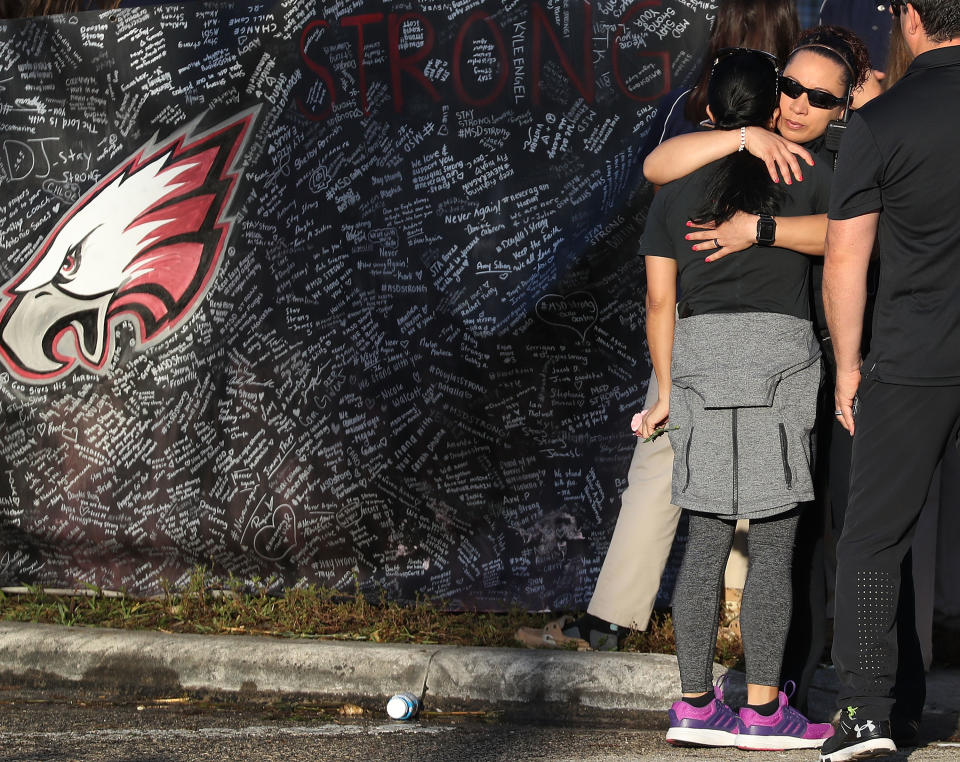 People hug each other as students arrive.