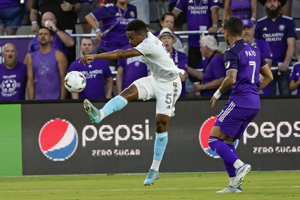 New England Revolution's Wilfrid Kaptoum (5) clears the ball away from Orlando City's Alexandre Pato (7) during the first half of an MLS soccer match Saturday, Aug. 6, 2022, in Orlando, Fla. (AP Photo/John Raoux)