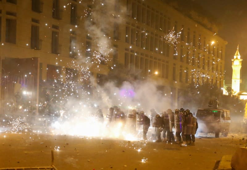 Fireworks are set off in front of police officers standing in postion behind riot shields during a protest against a ruling elite accused of steering Lebanon towards economic crisis in Beirut