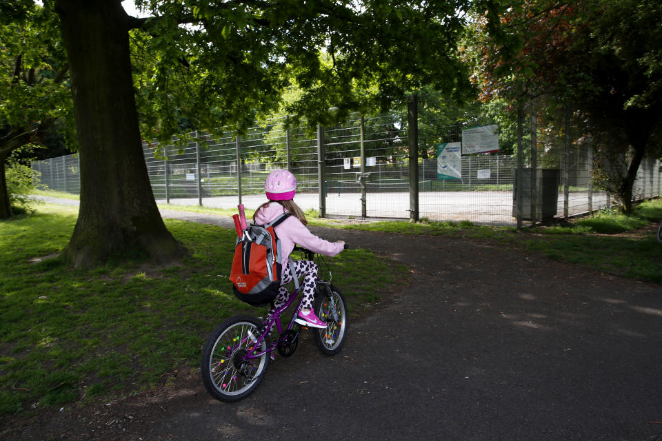 A young tennis player cycles up to the tennis courts at John Leigh Park in Altrincham.