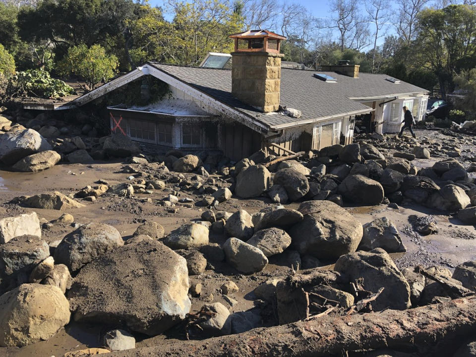 <p>Kerry Mann navigates the large boulders and mudflow that destroyed the home of her friend in Montecito, Calif., Wednesday, Jan. 10, 2018. The woman who lives in the home has not been seen since the early hours of Tuesday. (Photo: Mike Eliason/Santa Barbara County Fire Department via AP) </p>