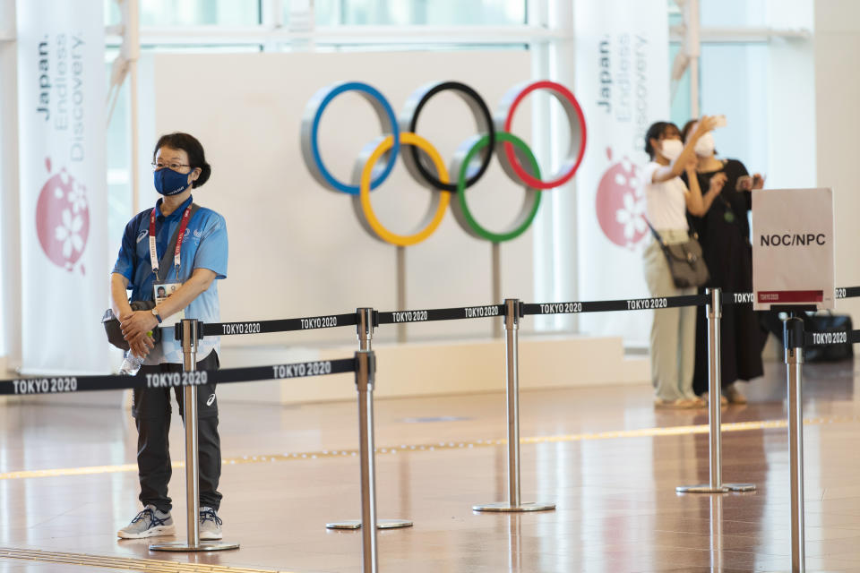 A Tokyo 2020 staff member stands by to help direct team members from other countries for the Tokyo 2020 Summer Olympic and Paralympic Games as they arrive at Haneda international airport in Tokyo on Sunday, July 18, 2021. (AP Photo/Hiro Komae)
