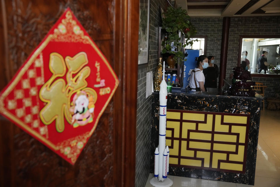 Restaurant staff work near a replica of a Chinese space rocket at a restaurant in the Jiuquan Satellite Launch Center near Jiuquan, China on Wednesday, June 16, 2021. China plans to launch three astronauts onboard the Shenzhou-12 spacecraft, who will be the first crew members to live on China's new orbiting space station Tianhe, or Heavenly Harmony, from the Jiuquan Satellite Launch Center in northwest China. (AP Photo/Ng Han Guan)