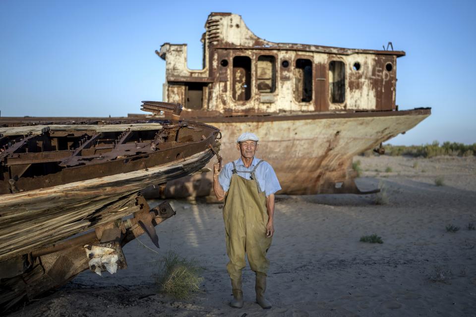 Coral Bai poses for a photo in front of an old boat in the area where the Aral Sea once was in Muynak, Uzbekistan, Thursday, July 13, 2023. (AP Photo/Ebrahim Noroozi)