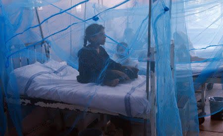 FILE PHOTO: A girl suffering from dengue fever sits under a mosquito net while seeking treatment at a hospital in Lahore September 20, 2011. To match Insight SANOFI-DENGUE/SCIENCE REUTERS/Mohsin Raza/File Photo