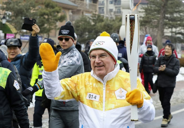 IOC president Thomas Bach carries the Olympic torch ahead of Friday's opening ceremony