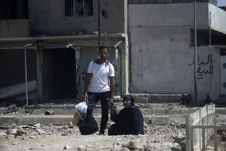 A man holds the hand of an elderly woman as they flee from clashes in western Mosul, Iraq May 27, 2017. REUTERS/Alkis Konstantinidis