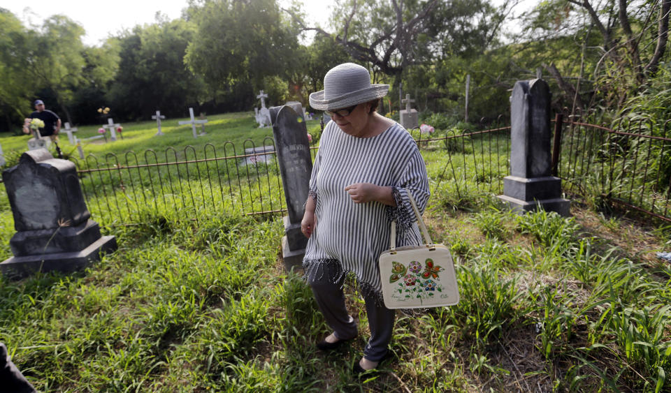 In this Wednesday May 1, 2019, photo, Alicia Jackson Flores, 68, and family walk around the the Eli Jackson Cemetery in San Juan, Texas. While the government has agreed to exempt some wildlife preserves and heritage properties from border wall construction, plenty of others remain under threat. (AP Photo/Eric Gay)