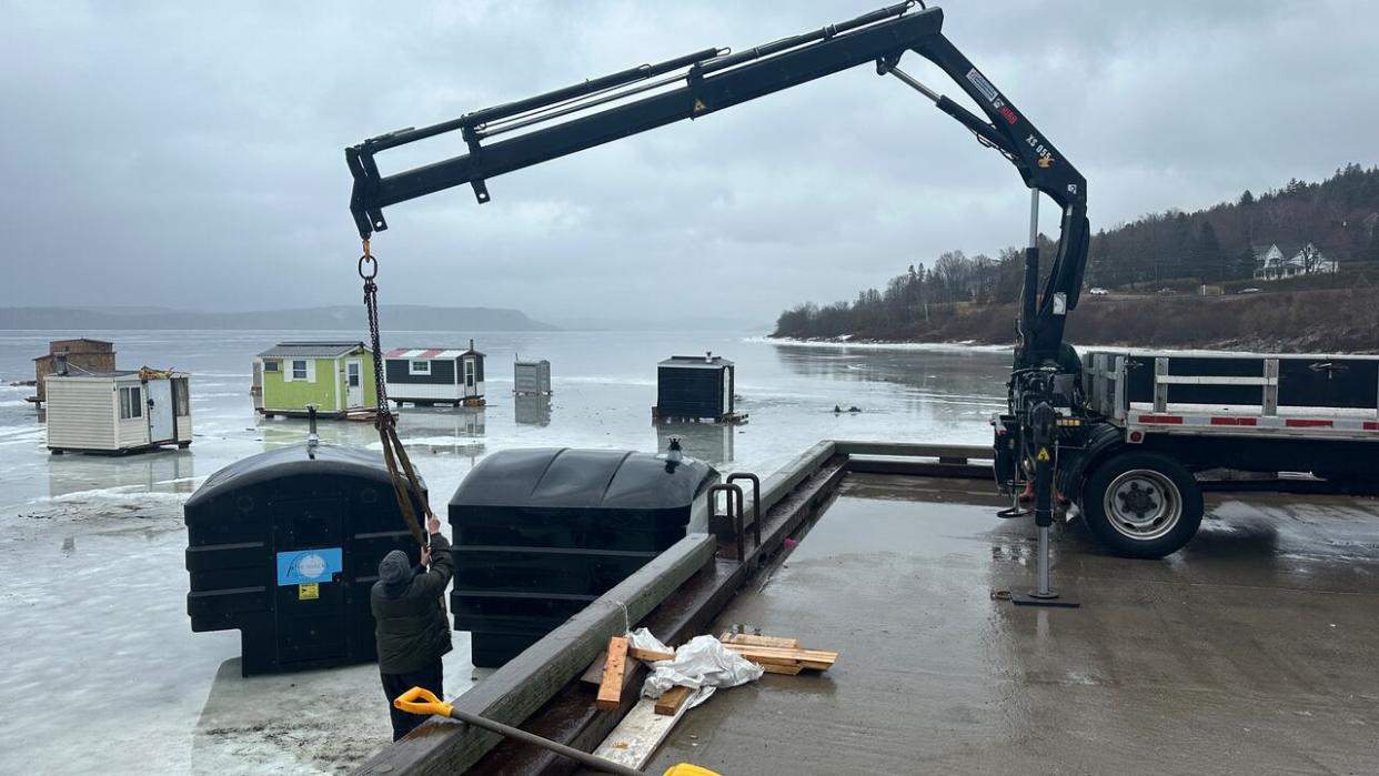 Crews were removing ice shacks at Renforth Wharf in Rothesay on Wednesday ahead of rainy, mild weather moving into the region. (Roger Cosman/CBC - image credit)