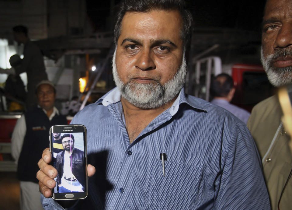 A relative shows the picture of Syed Areeb Ahmed, a Pakistani citizen who was killed the Christchurch mosque shooting, on his cell phone outside his home in Karachi, Pakistan, Saturday, March 16, 2019. Pakistan's foreign minister says at least six Pakistanis were killed in the New Zealand mosque shootings. Shah Mahmood Qureshi says authorities in Christchurch, where the shootings took place, are trying to determine whether three other Pakistanis who have been missing since Friday's attack were among the fatalities. (AP Photo/Fareed Khan)