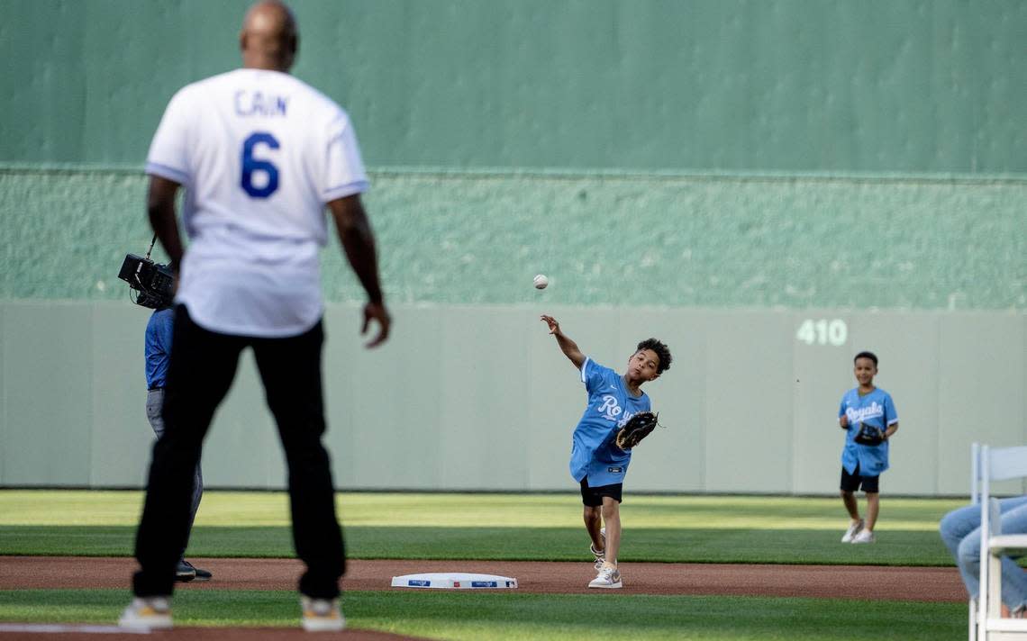 For the ceremonial first pitch, Cameron Cain, 8, completes a relay from center field and throws a ball to his dad and former Kansas City Royals center fielder Lorenzo Cain during a retirement ceremony at Kauffman Stadium on Saturday, May 6, 2023, in Kansas City. Cain signed a ceremonial one-day contract to retire as a Royal.