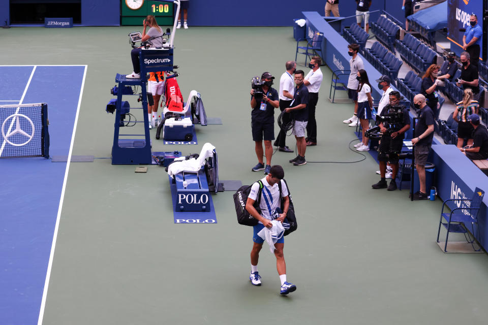 Novak Djokovic walks off the court after being defaulted due to inadvertently striking a lineswoman with a ball hit in frustration at the 2020 US Open.