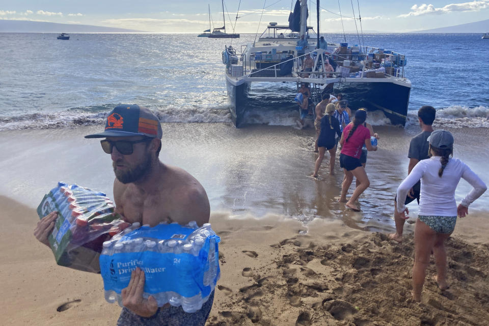 FILE - A group of volunteers who sailed from Maalaea Bay, Maui, form an assembly line on Kaanapali Beach on Aug. 12, 2023, to unload donations from a boat. When the most deadly U.S. fire in a century ripped across the Hawaiian island, it damaged hundreds of drinking water pipes, resulting in a loss of pressure that likely allowed toxic chemicals along with metals and bacteria into water lines. Experts are using strong language to warn Maui residents in Lahaina and Upper Kula not to filter their own tap water. (AP Photo/Rick Bowmer, File)